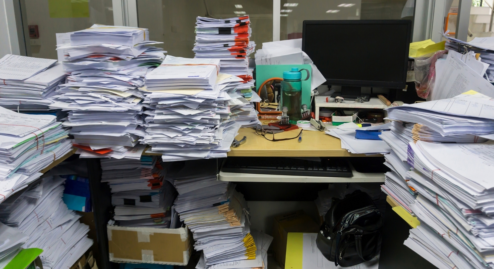 Desk buried in paper — when systems don't close the gap.
