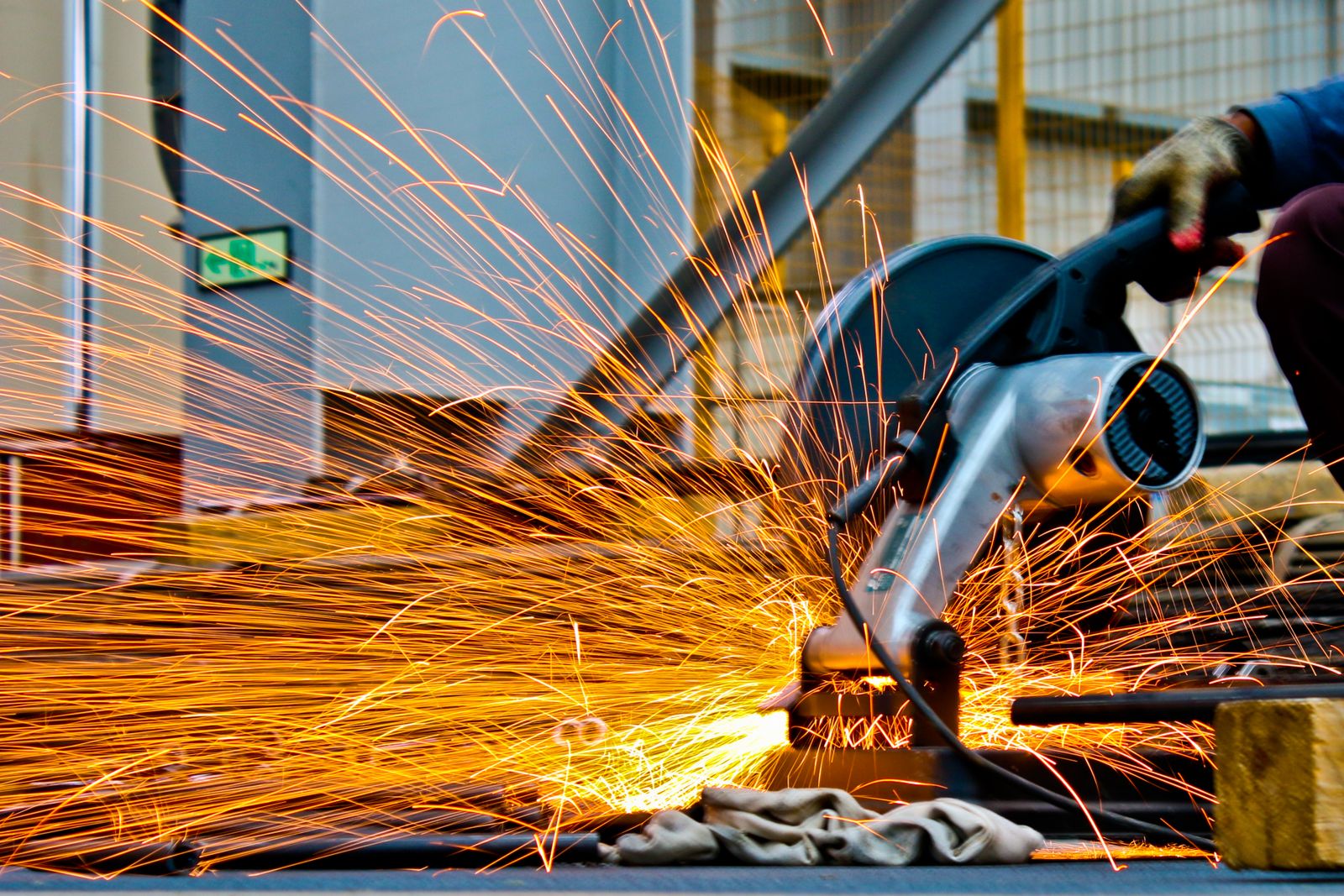 Sparks off a chop saw cutting steel on a fabrication floor.