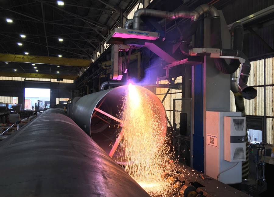 CNC plasma machine cutting and bevelling large-diameter pipe on a fabrication floor